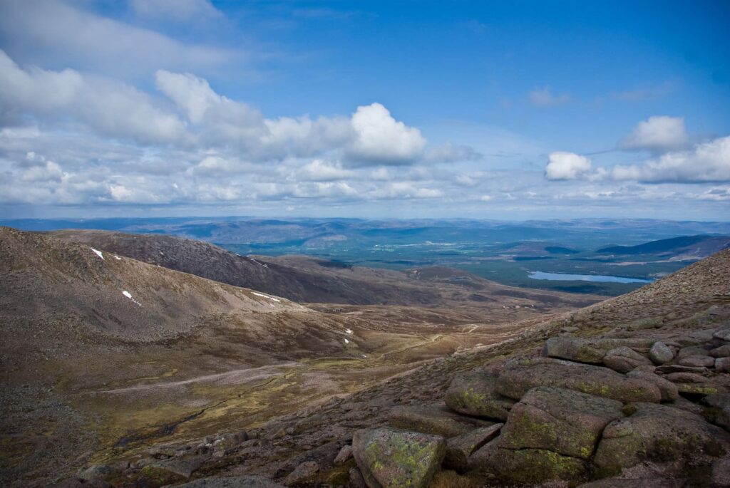 Felsige Berghänge mit Wald und einem See in der Ferne bei Aviemore