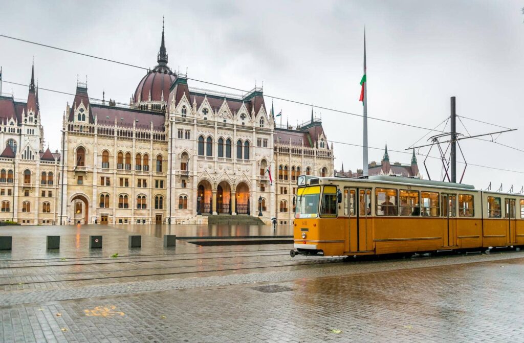 Gelbe Straßenbahn vor dem ungarischen Parlament in Budapest