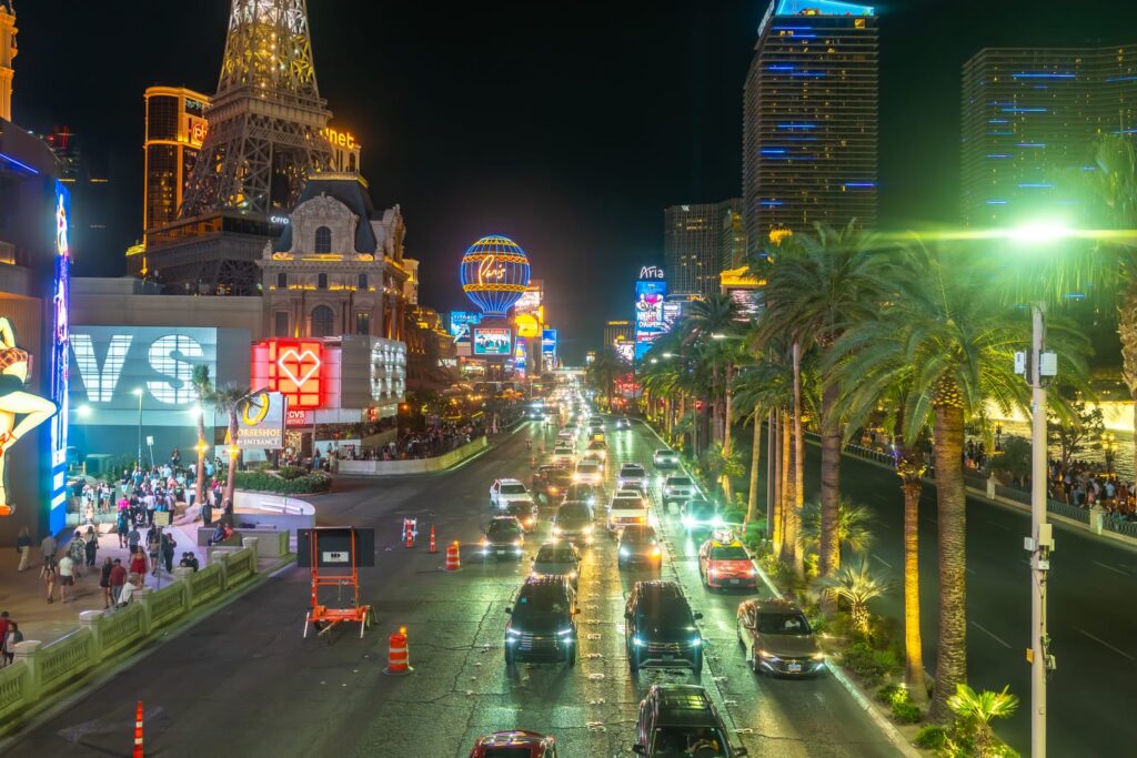 Verkehr, Palmen und beleuchtete Hotels am Las Vegas Strip bei Nacht