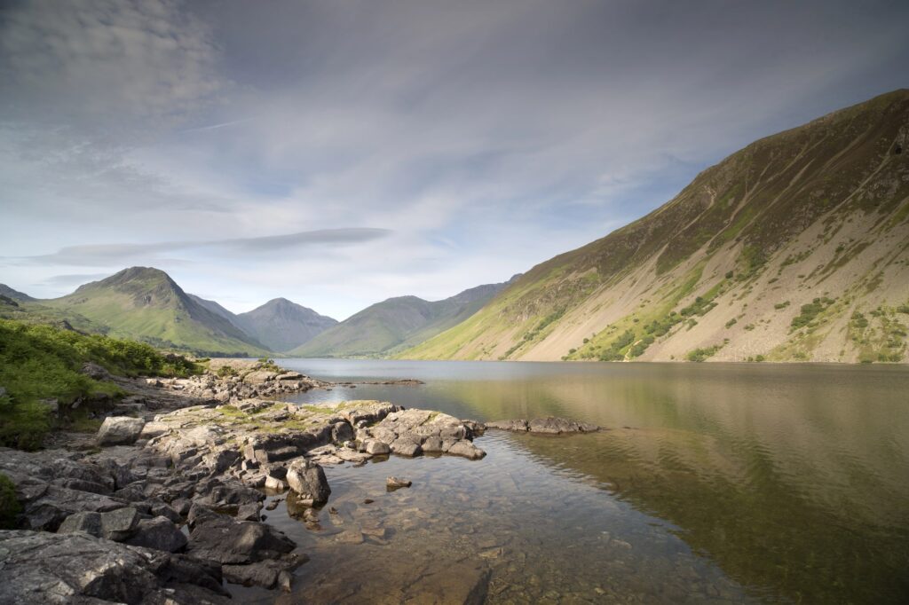 Felsiges Seeufer und steile Hänge unter Wolken im Lake District