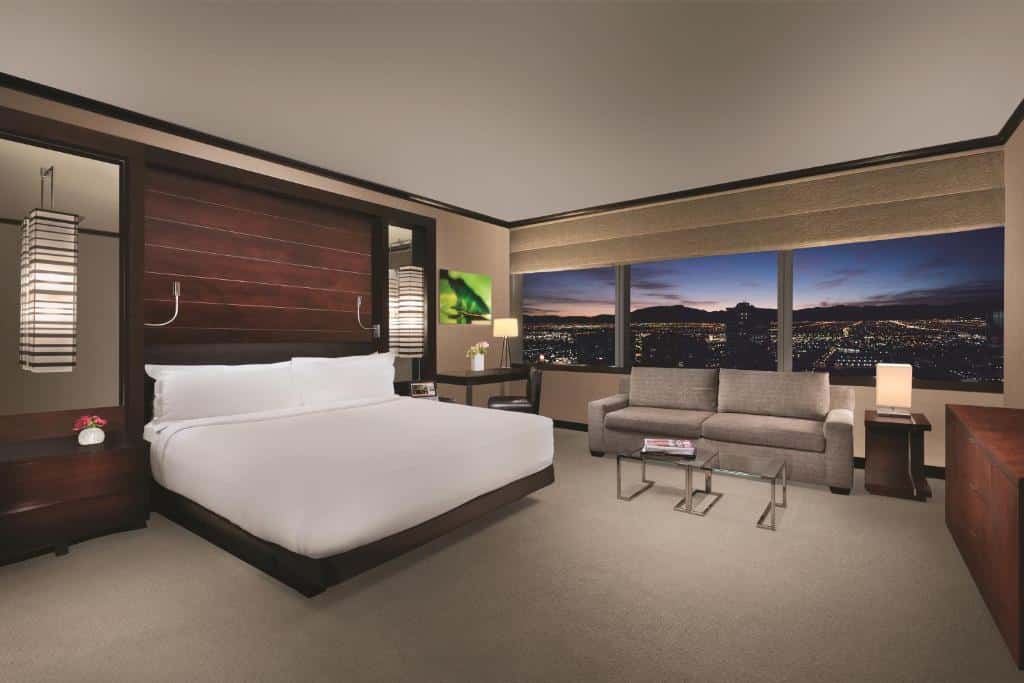 Bett und Sitzbereich neben großen Fenstern in einer Suite im Vdara Hotel & Spa