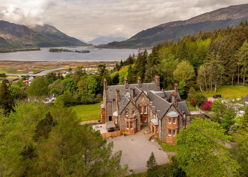 Glencoe House zwischen Bäumen mit einem See und Bergen im Hintergrund