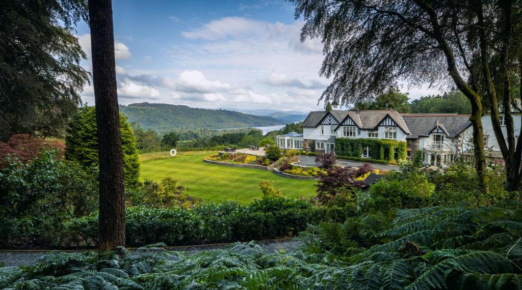 Blick über Rasen und einen kleinen Teich zwischen Bäumen auf das Linthwaite House Hotel