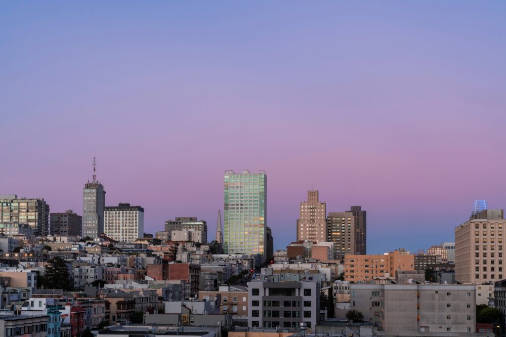 Blick über Gebäude und Hügel von San Francisco unter einem rosa Abendhimmel