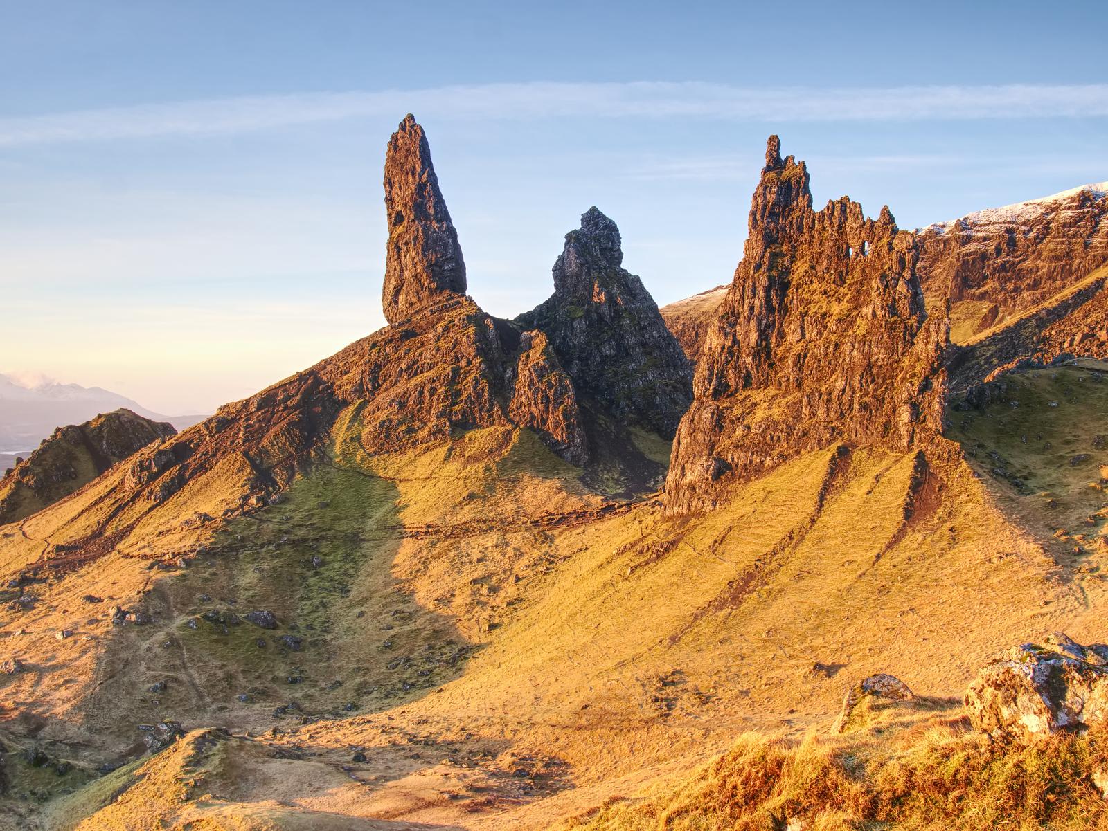 Felsnadeln des Old Man of Storr über sonnenbeschienenen Hängen auf der Isle of Skye