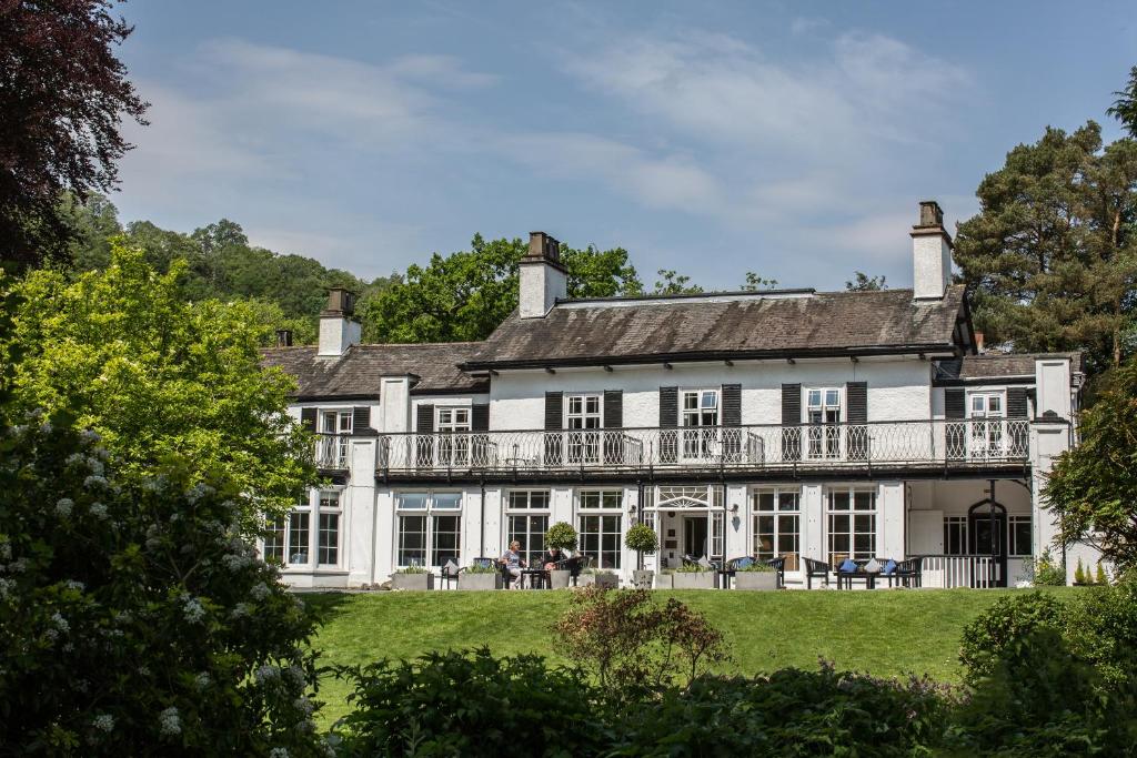 Weiße Fassade und Balkon des Rothay Manor Hotels zwischen Bäumen im Garten
