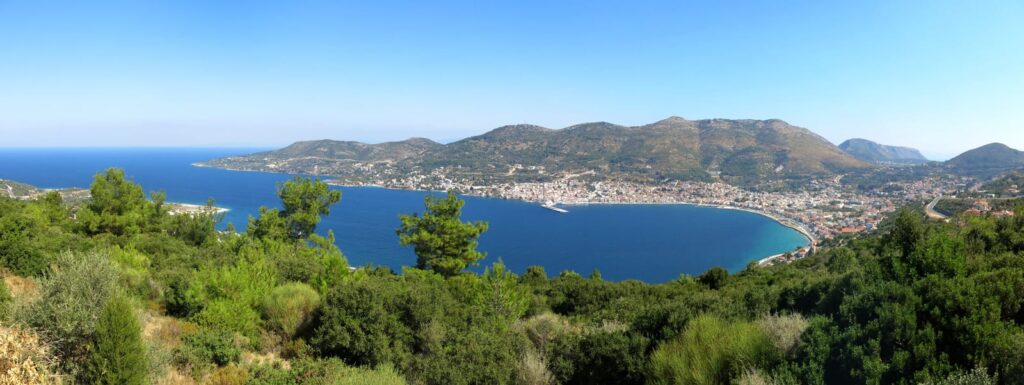 Weiter Blick über eine Bucht auf Samos mit bewaldeten Hängen und Häusern an der Küste