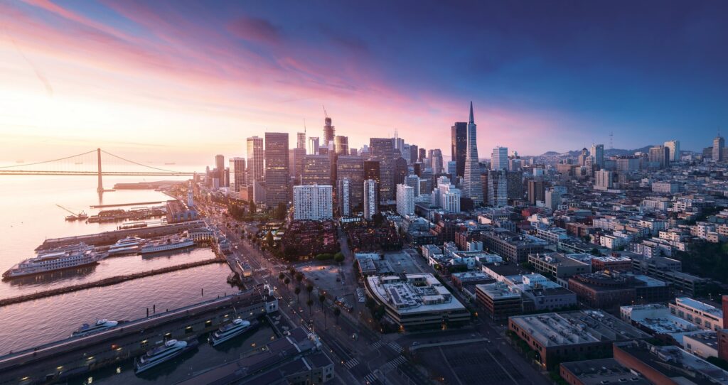 Luftaufnahme des Financial Districts, der Uferpromenade und der Piers bei Sonnenuntergang