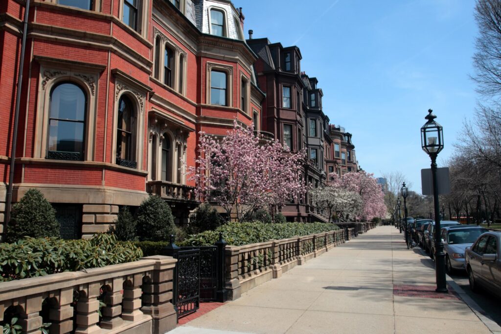 Backsteinhäuser, blühende Bäume und Geländer entlang eines Gehwegs in Back Bay