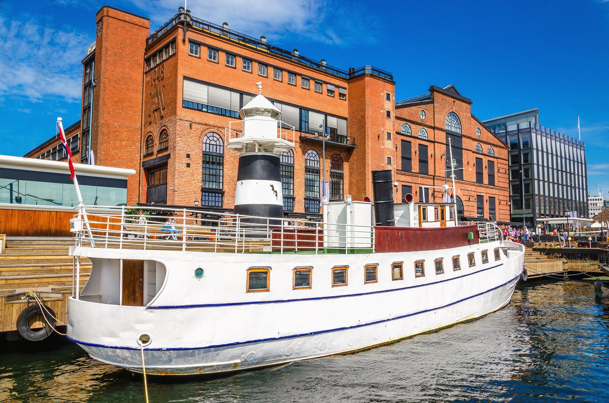 Aker Brygge in Oslo mit einer weißen Jacht im Hafen
