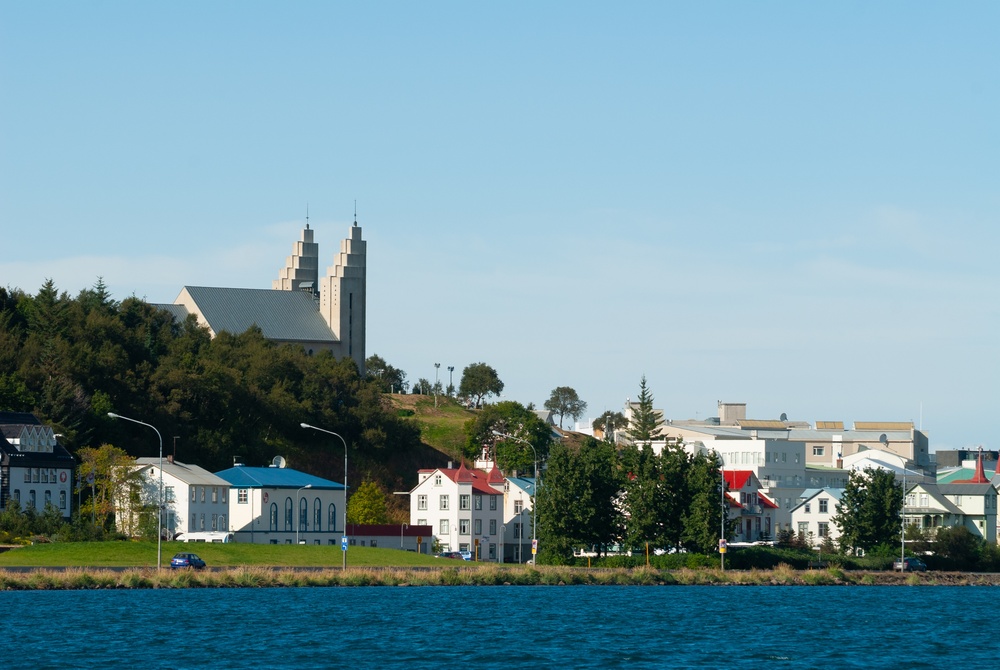 Akureyri über den Fjord Eyjafjörður hinweg gesehen, mit bunten Häusern am Wasser und der Kirche über der Stadt