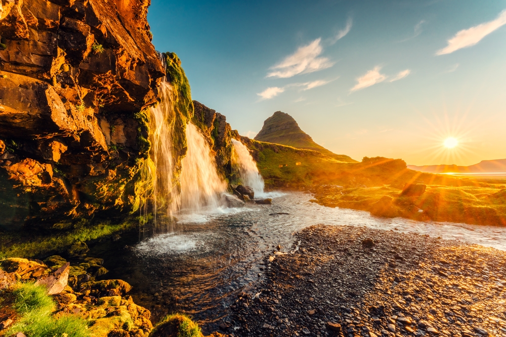 Der Berg Kirkjufell und der Wasserfall Kirkjufellsfoss auf Snæfellsnes bei Sonnenaufgang