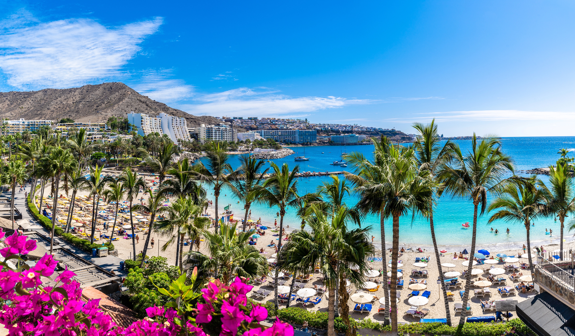 Der Strand Anfi del Mar auf Gran Canaria mit Palmen, Sonnenschirmen und türkisblauem Wasser