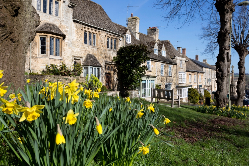 Steinhäuser und Osterglocken am Hang in Burford
