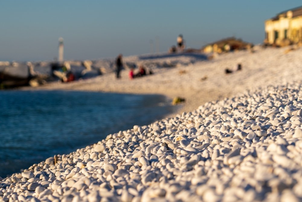 Strand mit weißen Steinen und Wellenbrechern in Marina di Pisa