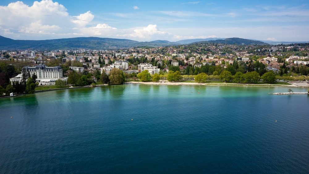 Luftaufnahme von Annecy und dem türkisfarbenen See Lac d'Annecy mit den Bergen im Hintergrund