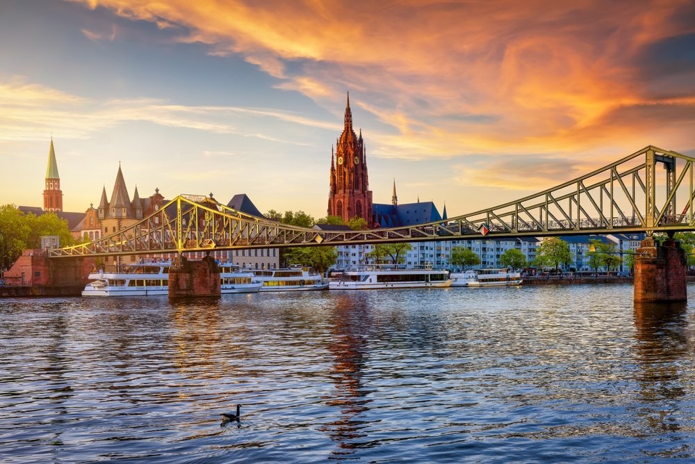 Skyline von Frankfurt mit dem Eisernen Steg und dem Kaiserdom über dem Main bei Sonnenuntergang