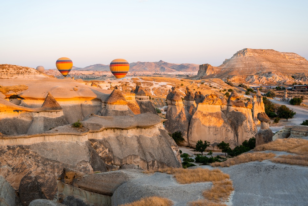 Heißluftballons schweben bei Sonnenaufgang über den Felsformationen in Kappadokien