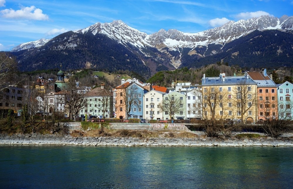 Wo man in Innsbruck übernachten sollte: die bunten Häuser entlang des Inns mit der Nordkette im Hintergrund