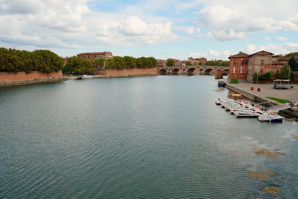 Die Garonne und die Brücke Pont Neuf in Toulouse mit den rosafarbenen Backsteinhäusern entlang des Kais