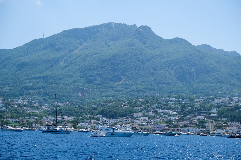 Der Berg Epomeo und ein Hafenort auf Ischia mit ankernden Booten im Vordergrund